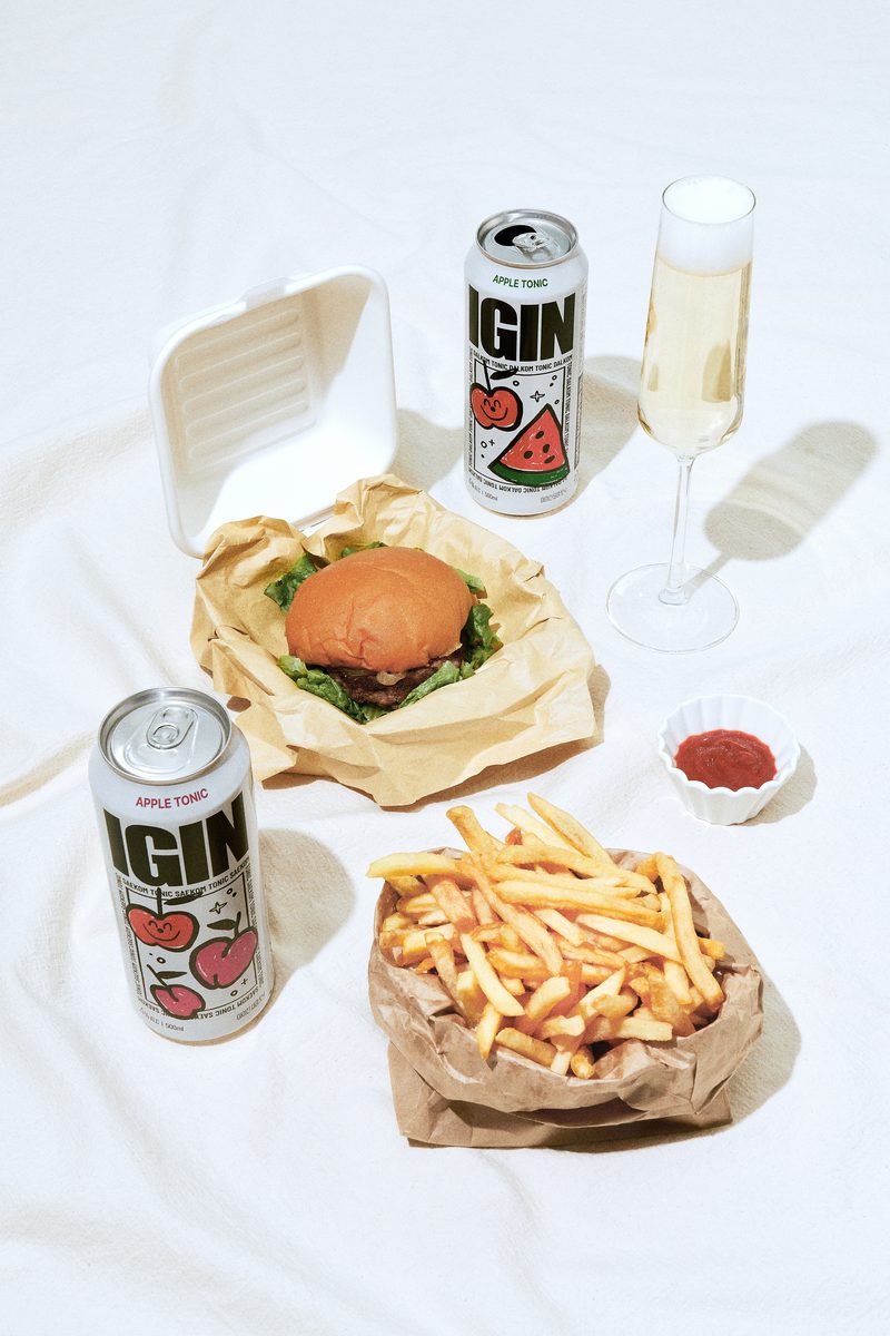 A burger, fries and two Apple Tonic cans