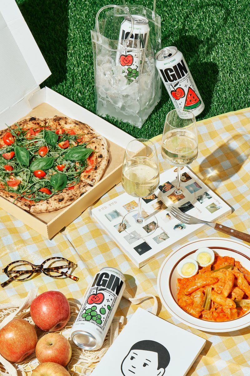 A picnic table with pizza and Apple Tonic cans